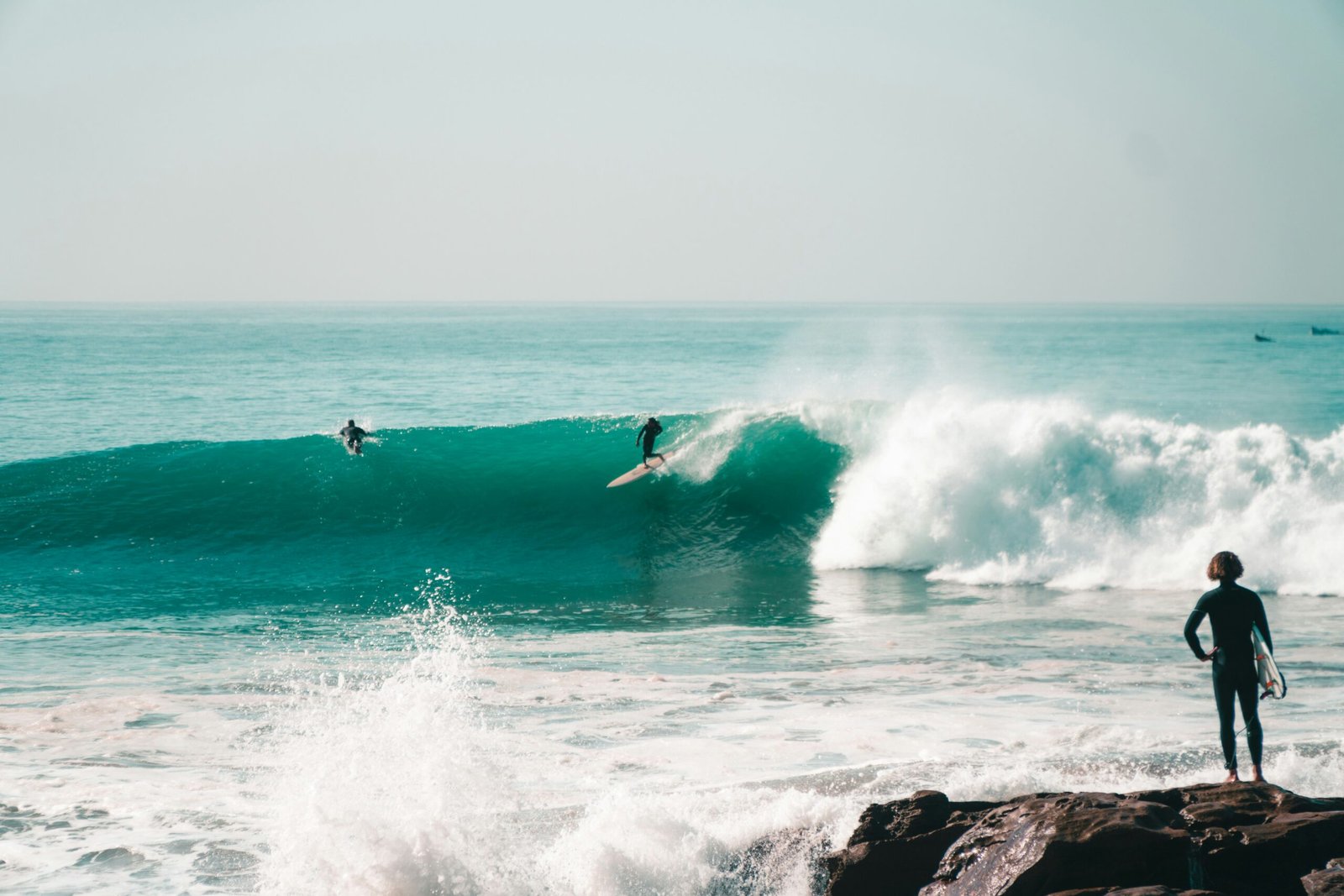 Surfer catching a clean right-hand wave during a perfect sunny day in Taghazout, Morocco — showcasing the ideal conditions for surf in Taghazout, one of the most popular surf destinations in North Africa.